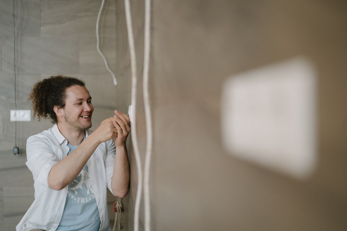 Electrician working at a wall outlet during an electrical repair