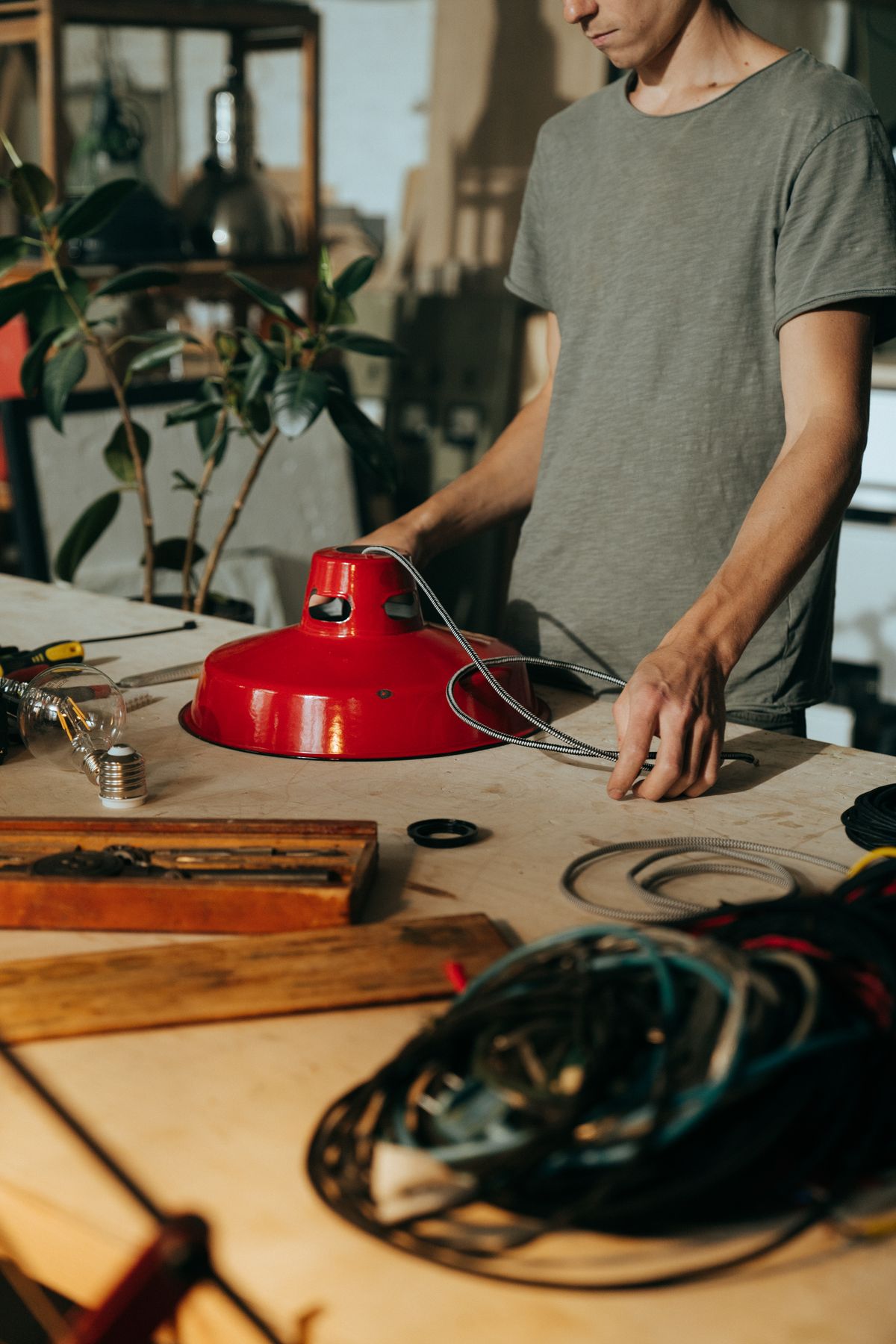 Craftsman handling a light fixture and wiring during a lamp repair