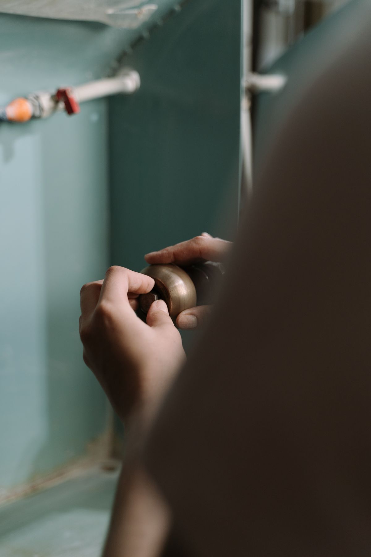 Hands working on plumbing connections beneath a kitchen sink